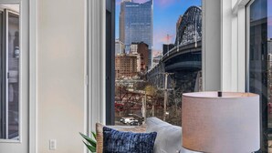 A room with a large window offering a view of a cityscape including a tall building and a bridge. - City Getaway, Free Parking, 24/7 Hour Gym (Cleveland)