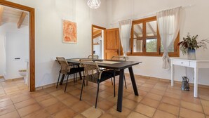 Un coin repas avec une table et des chaises en bois, un bureau blanc et une fenêtre avec des rideaux.