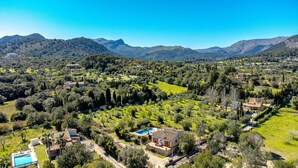 Un paysage rural parsemé de maisons, avec une piscine et des montagnes en arrière-plan.