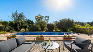 Un espace aménagé au bord de la piscine, comprenant une piscine, du mobilier d’extérieur et des plantes en pot.
