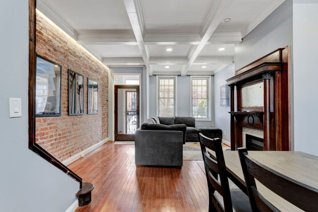 A spacious living area with a brick accent wall, a fireplace, and a dining table.