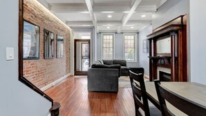 A spacious living area with a brick accent wall, a fireplace, and a dining table.