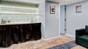 A modern bathroom with a vanity, a shower area, and a green upholstered chair.