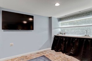A room with a flat-screen TV mounted on the wall, a window with a view, and a small table with a sink. - Phoenix`s Place Cap Hill | King Bed | Walk to H St (Washington)