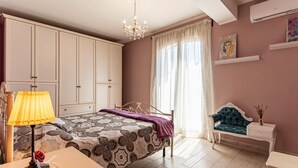 Una camera da letto con un letto, un comodino, una lampada, una cassettiera e un'anta con tende.