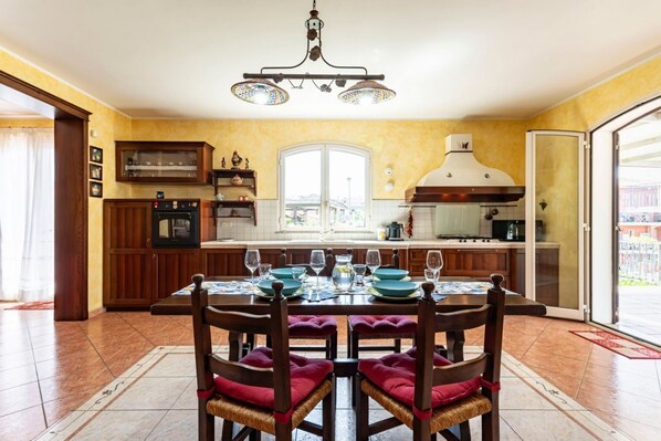 A dining area with a table set for four, a kitchen with a stove and oven, and a large window.