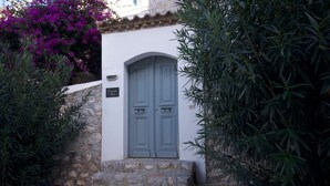 A white building with a grey door, stone steps, and a sign that reads "Pavlos Place". - Elegant Hydra Getaway (Idra)