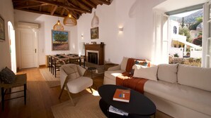 A cozy living room with a fireplace, wooden ceiling, and a view of the outside. - Elegant Hydra Getaway (Idra)