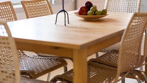 A dining area with a round table, wicker chairs, a candle, and a fruit bowl. - Villa Alethea Retreat (Idra)