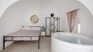 Ein Schlafzimmer mit Bett, Nachttisch, Schminktisch, Badewanne und Spiegel.
