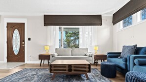 Un salon avec un canapé beige, un canapé bleu, une table basse en bois et un tapis à motifs.