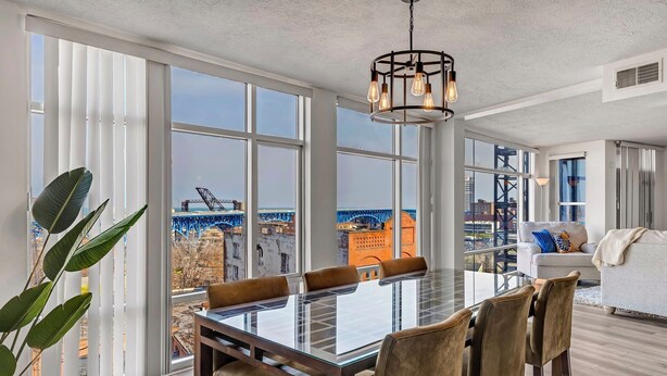 A dining area with a large table and chairs, large windows, and a view of a cityscape. - 2-bedroom apartment in brilliant Cleveland with WiFi, AC, fitness room (Cleveland)