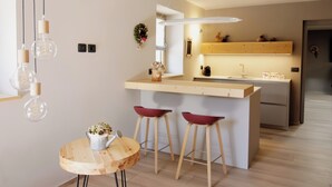 A modern kitchen with a central island, wooden stools, and pendant lighting. - Villa Cavazzal - Exclusive apartment (Cavalese)