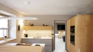 A modern kitchen with a central island, wooden cabinets, and built-in appliances. - Villa Cavazzal - Exclusive apartment (Cavalese)