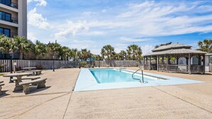 Una piscina con muelle de madera, palmeras y un pabellón.