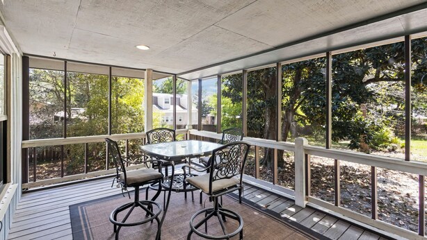A covered patio with a table and chairs, large windows, and a view of trees and a house. - Cheyenne Retreat Pet Friendly Boater's Paradise (Orange Beach)