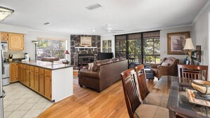 A spacious living area with a large brown leather sofa, a dining table with chairs, a kitchen with wooden cabinets, and a stone fireplace. - Cheyenne Retreat Pet Friendly Boater's Paradise (Orange Beach)
