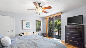 A bedroom with a bed, a ceiling fan, a TV, a dresser, and a sliding glass door leading to a balcony. - Cheyenne Retreat Pet Friendly Boater's Paradise (Orange Beach)