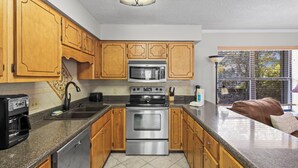 A kitchen with wooden cabinets, a stainless steel oven, a microwave, and a coffee maker. - Cheyenne Retreat Pet Friendly Boater's Paradise (Orange Beach)