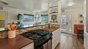A modern kitchen with a large island, wooden cabinets, and a gas stove. - Dream 2-Story Home w/Deck, A/C, Hot Tub, Gas Grill, W/D - Walk to the Beach (San Diego)