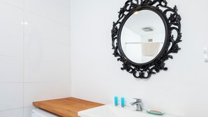 A modern bathroom with a white sink, black ornate mirror, and a washing machine. - Loft Hideaway Studio (Łódź)