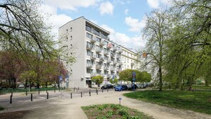 Un edifici d'apartaments de diverses plantes amb balcons, zona d'aparcament i jardí paisatjista.