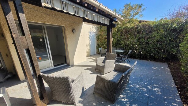 A patio with wicker furniture and a sliding glass door leading to a covered area. - CAP D'AGDE - Plage de la Roquille / Réf 251 (CAP D'AGDE)