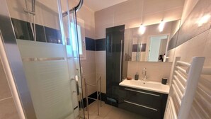 A modern bathroom with a glass shower enclosure, a sink with a mirror, and a towel rack. - CAP D'AGDE - Plage de la Roquille / Réf 251 (CAP D'AGDE)