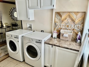 Convenient laundry area with two front-loading washing machines and ample storage.