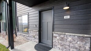 A house with a gray door, a number 693 sign, and a stone base. - Modern 2-BR Townhome w/ Garage, AC & Workspace (Driggs)
