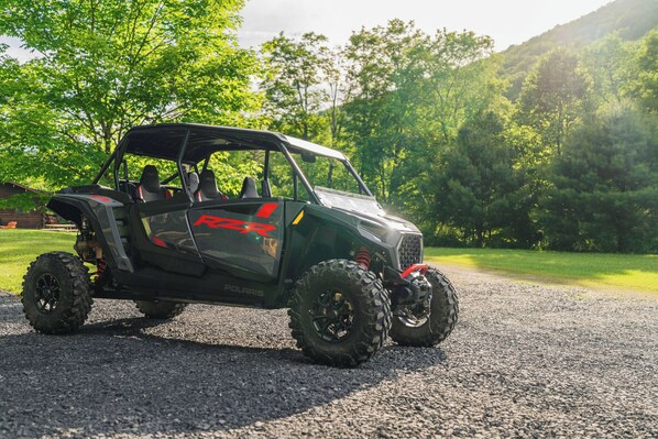 A Polaris RZR vehicle on a gravel path with greenery in the background.