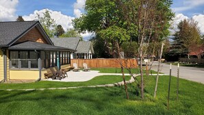 Une maison dotée d’un patio couvert, d’une cour clôturée et d’une pelouse bien entretenue.