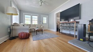 Un salon avec un canapé, une table basse, un tapis et un téléviseur posé sur un meuble.