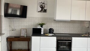 A kitchen with white cabinets, a microwave, a stove, and a sink. - Bnbook Residenza Vespucci 2 (sedriano)