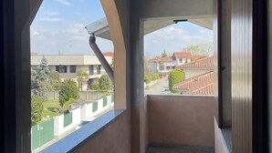 A balcony with a view of a residential area, featuring a concrete floor and a red mat. - Bnbook Residenza Vespucci 2 (sedriano)