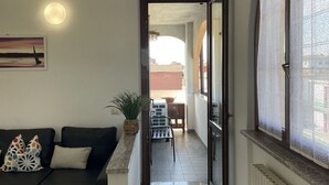 A living room with a sofa, a potted plant, and a painting on the wall. - Bnbook Residenza Vespucci 2 (sedriano)