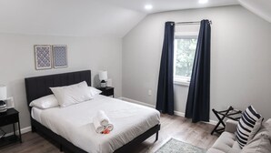 A modern bedroom with a large bed, bedside tables, a chair, and a window with curtains.