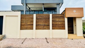Un edificio moderno con fachada de madera, un letrero que dice 'CASA LIBERTAS PREMIUM SUITES', y un camino de grava.