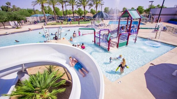 Un parque acuático con una piscina grande, toboganes y una estructura de juegos.