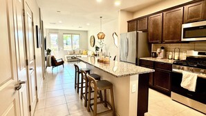 Una cocina moderna con armarios de madera oscura, electrodomésticos de acero inoxidable y una isla grande con taburetes de bar.