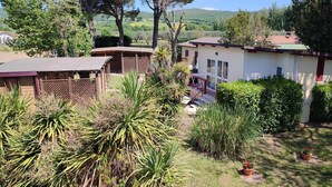 A residential property with a fenced yard, a small building with a red roof, and a large tree in the background. - Bungalow 'Camping Massimo -  2' with Lake View, Private Terrace and Private Garden (Bolsena)