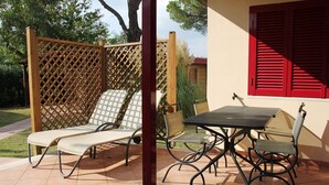 A patio with a table and chairs, a wooden lattice screen, and a red shuttered window. - Bungalow 'Camping Massimo -  2' with Lake View, Private Terrace and Private Garden (Bolsena)