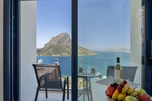 Un balcone con tavolo, sedia e un cesto di frutta con una bottiglia di vino.