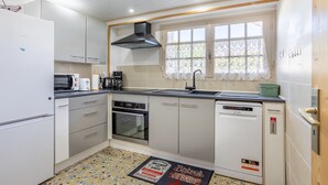 A compact kitchen with white cabinets, a microwave, a toaster, a sink, and a dishwasher. - Apartment 'Appartement Entre Mer Et Marais' with Shared Terrace, Wi-Fi and Air Conditioning (Challans)