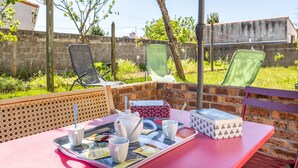 An outdoor patio with a table set for a meal, including a tray with cups, a teapot, and a box. - Apartment 'Appartement Entre Mer Et Marais' with Shared Terrace, Wi-Fi and Air Conditioning (Challans)