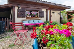 A rustic building with a wooden bench and a red folding chair outside.