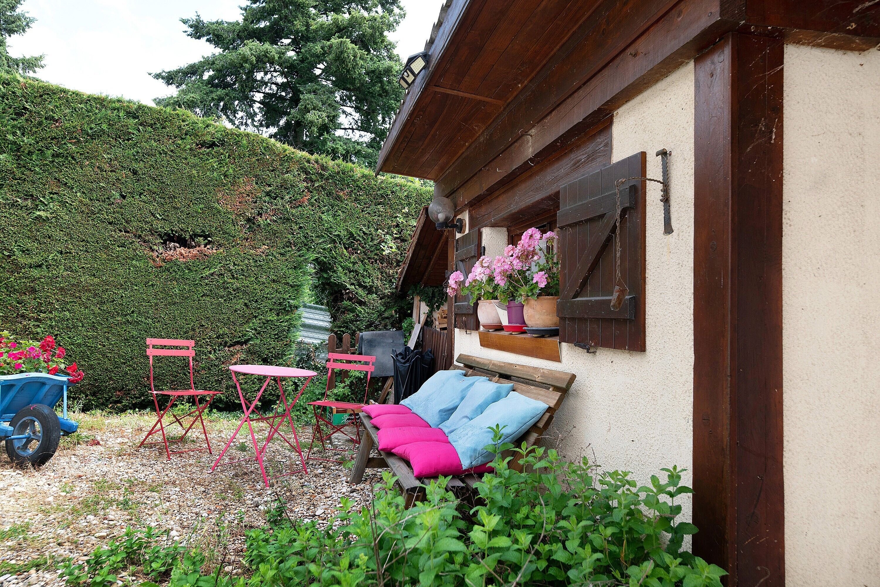 Un jardin avec un banc en bois, une chaise pliante et une brouette.