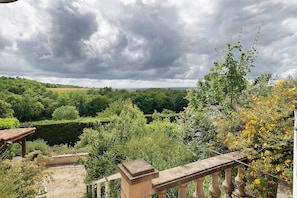 Ein Garten mit Steinsims, üppigem Grün und Blick auf ein entferntes Feld.