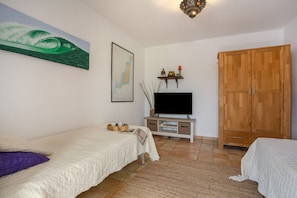 A bedroom with a bed, a TV, a wardrobe, and a painting on the wall.