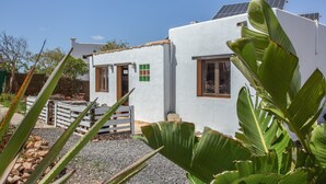 Ein weißes Gebäude mit kleinem Eingang, Solaranlage auf dem Dach und einer Auffahrt mit Kies.
